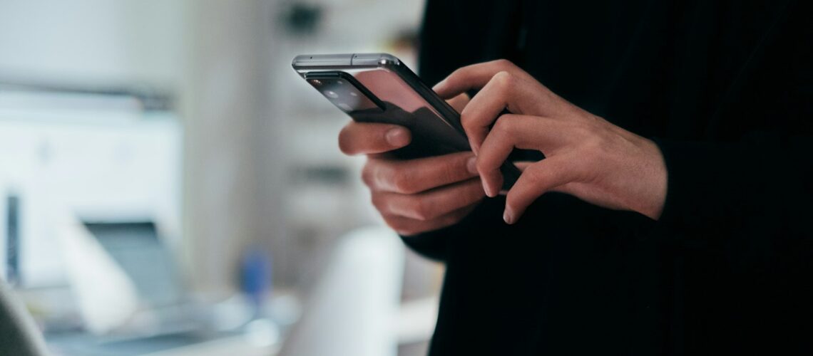 Person typing a message on a smartphone in an office