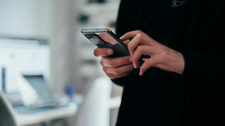 Person typing a message on a smartphone in an office